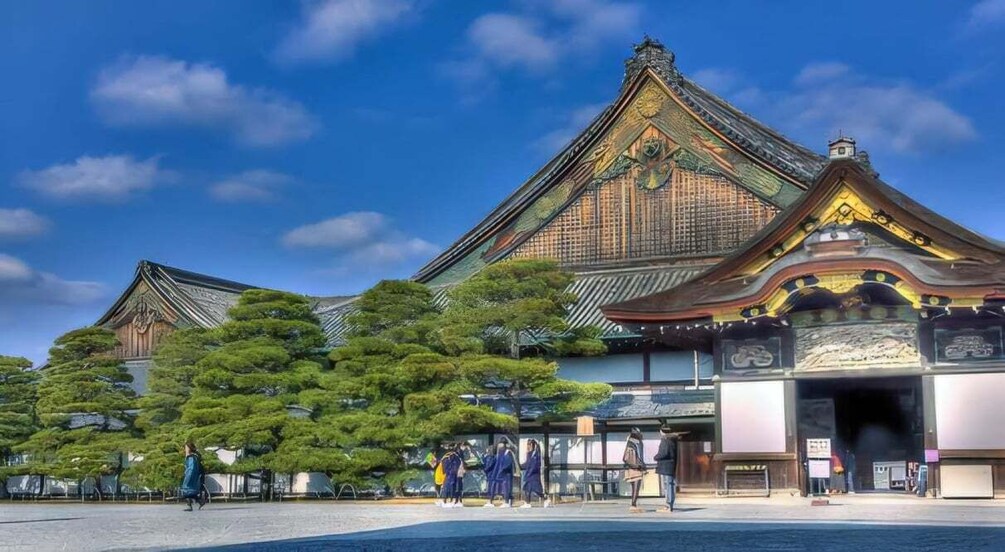A traditional Japanese building with a large, ornate roof and a well-maintained garden with pine trees. 1