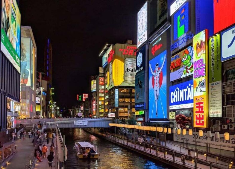 A brightly lit urban street at night with illuminated billboards and a river. 3
