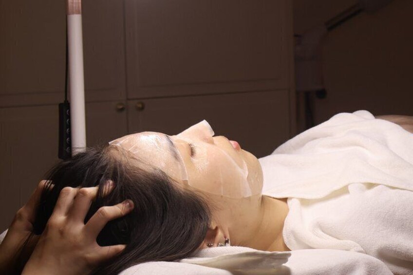 A person lying down with a white towel and a face mask on. 2