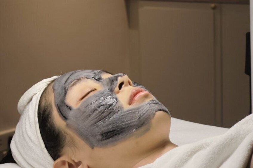 A person lying down with a towel wrapped around their head, in a room with a door in the background. 5