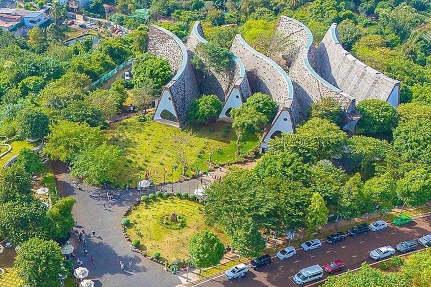 A park with unique curved buildings, a circular lawn, and a parking area. 2