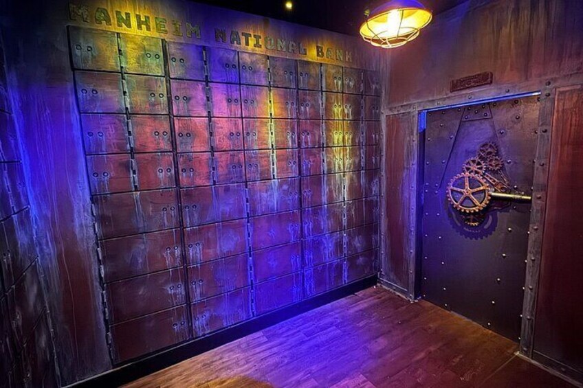 A room with a metal wall displaying lockers and a large door with a gear mechanism. 2