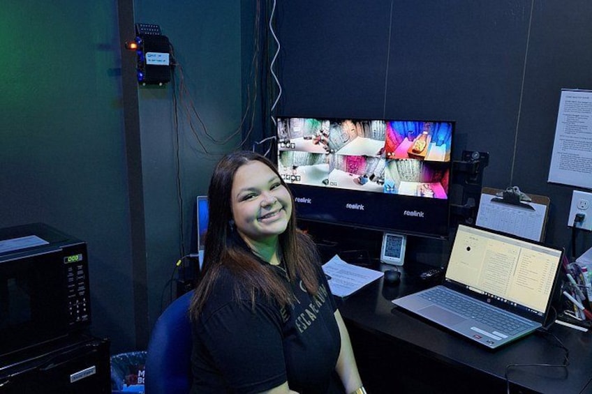 A person sitting at a desk with a computer monitor displaying a colorful image, a laptop, and various office equipment. 3