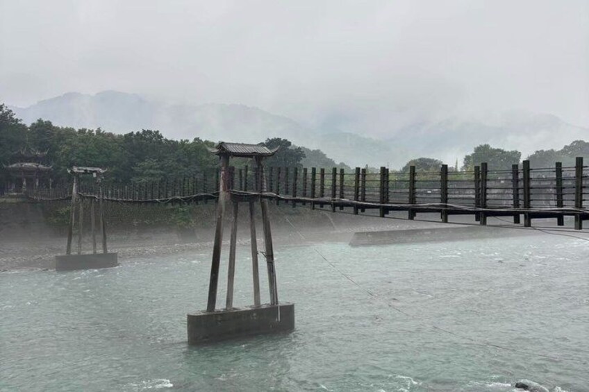 A wooden bridge over water with a mountainous backdrop. 3