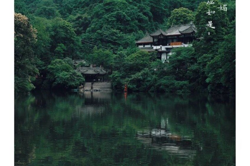 A traditional building surrounded by lush greenery and a calm body of water. 5
