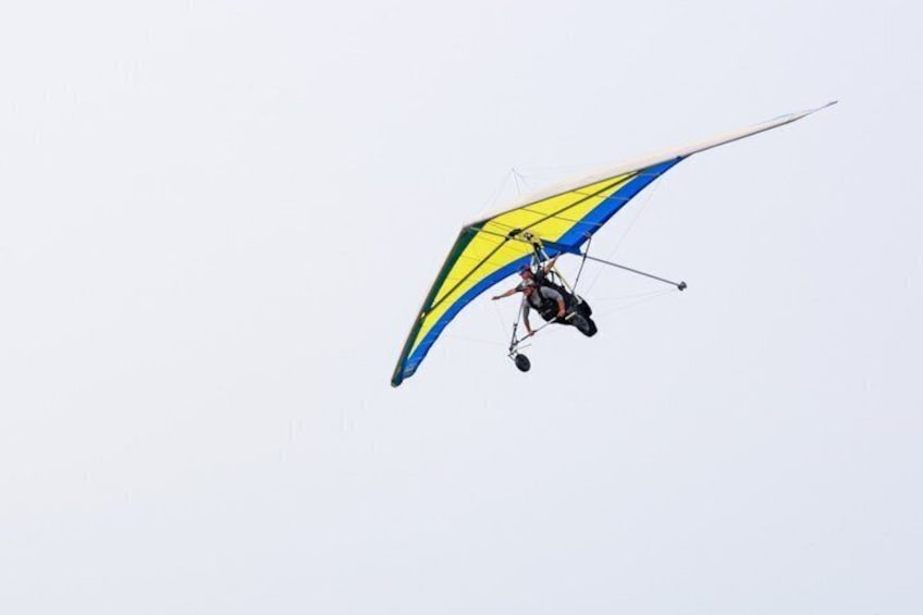 A hang glider with a yellow and blue sail flying against a clear sky. 5