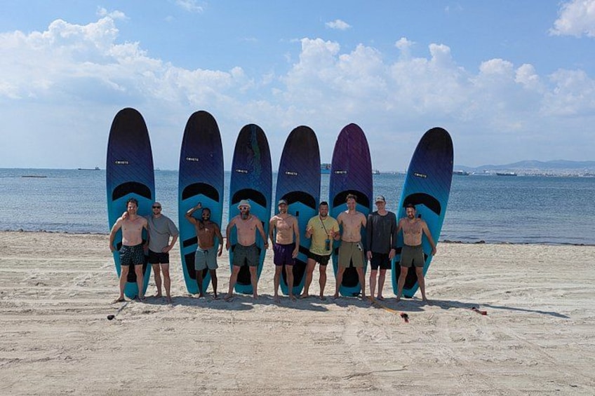 A group of people standing on a beach with surfboards. 1