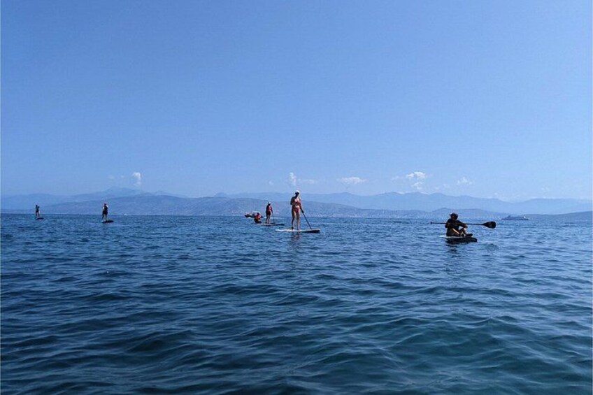 People paddleboarding on a calm sea with mountains in the background. 4