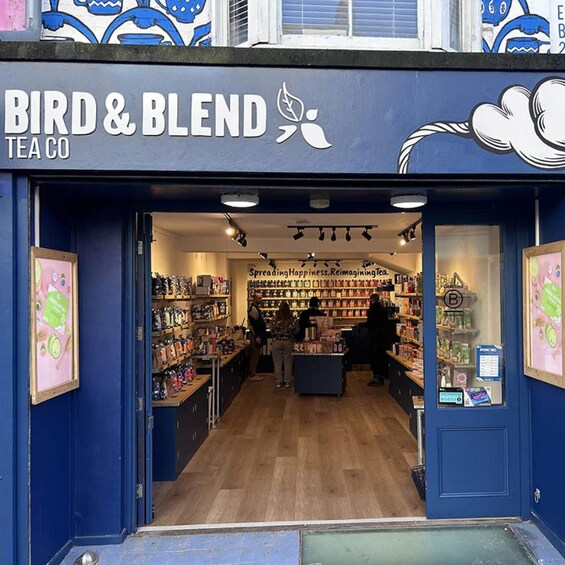 The entrance to Bird & Blend Tea Co., featuring a blue storefront and interior with shelves stocked with tea products. 4