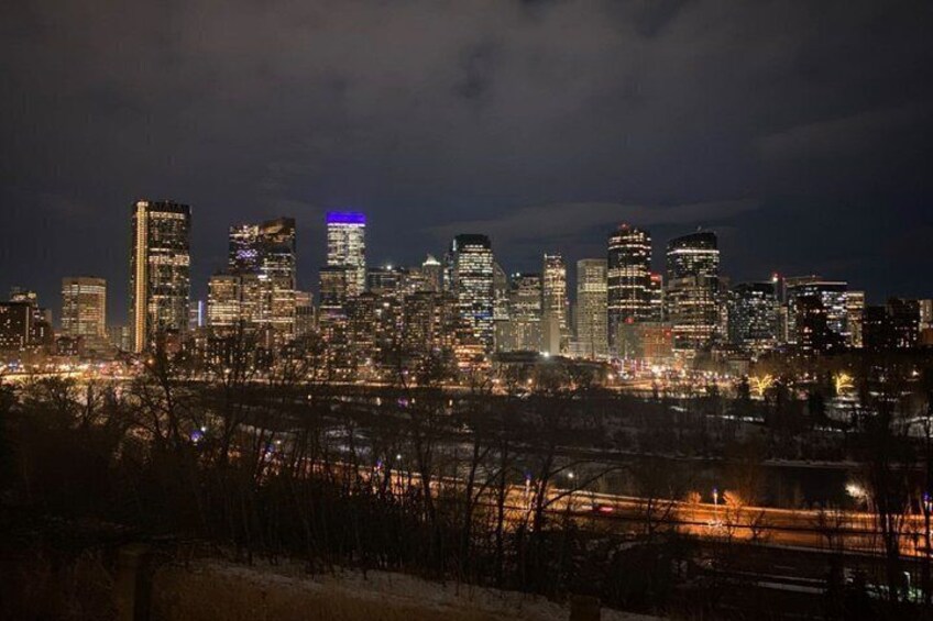 A city skyline at night with illuminated buildings and a river in the foreground. 1