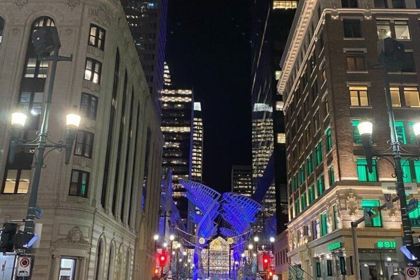 A city street at night with illuminated buildings and a large, colorful structure in the center. 5