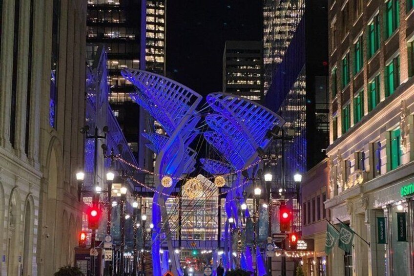 A city street at night with illuminated blue structures and buildings in the background. 4