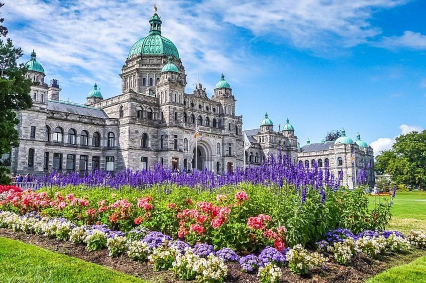 A historic building with green domes and a well-maintained garden with colorful flowers. 1