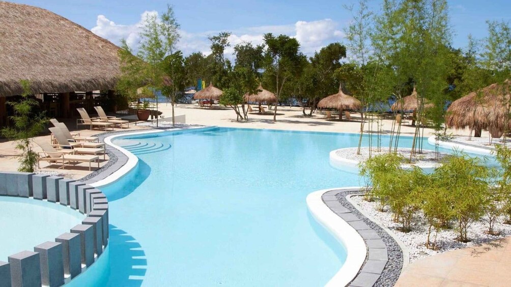 A resort pool with lounge chairs and thatched umbrellas. 3