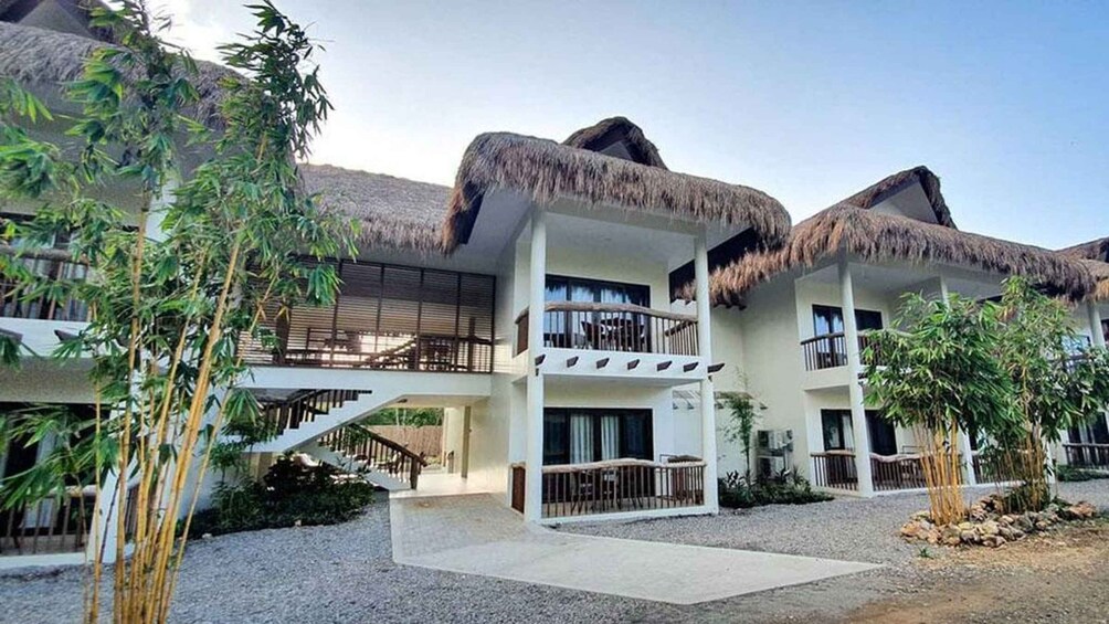 A resort with thatched-roof buildings, a covered walkway, and lush greenery. 4