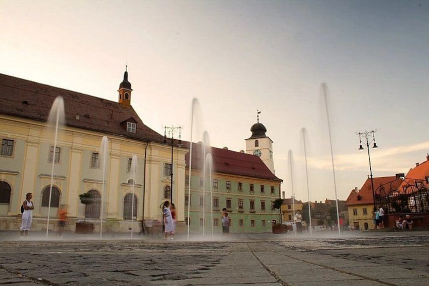A historic building with a fountain in front, a clock tower, and a church with a dome. 3