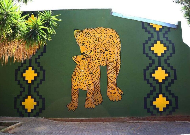 A mural of a mother and cub on a green wall with yellow geometric patterns. 1
