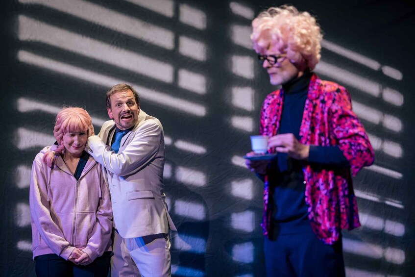 Three people on a stage with a patterned backdrop. 3