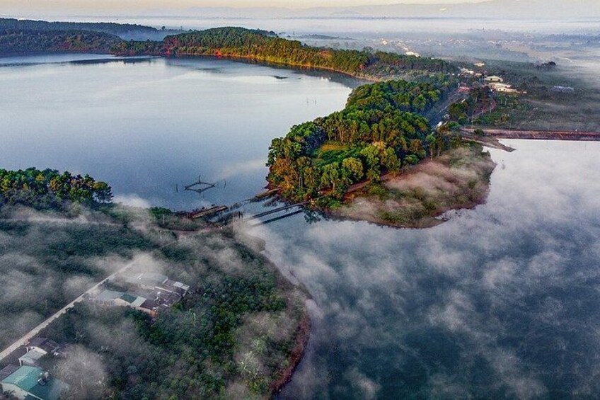 A lake surrounded by forested areas, a small island with trees, and a distant shoreline. 4