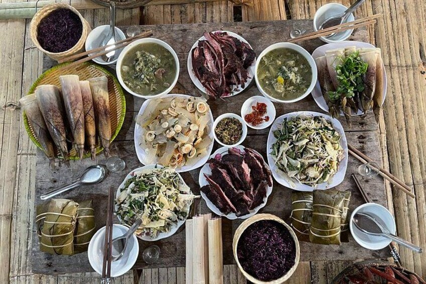 A variety of dishes arranged on a wooden table, including bowls of soup, plates of meat, and other food items. 4