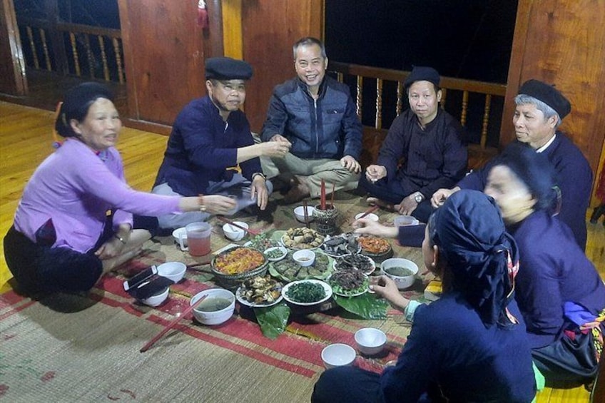 A group of people sitting around a table with various dishes, engaged in a meal. 1