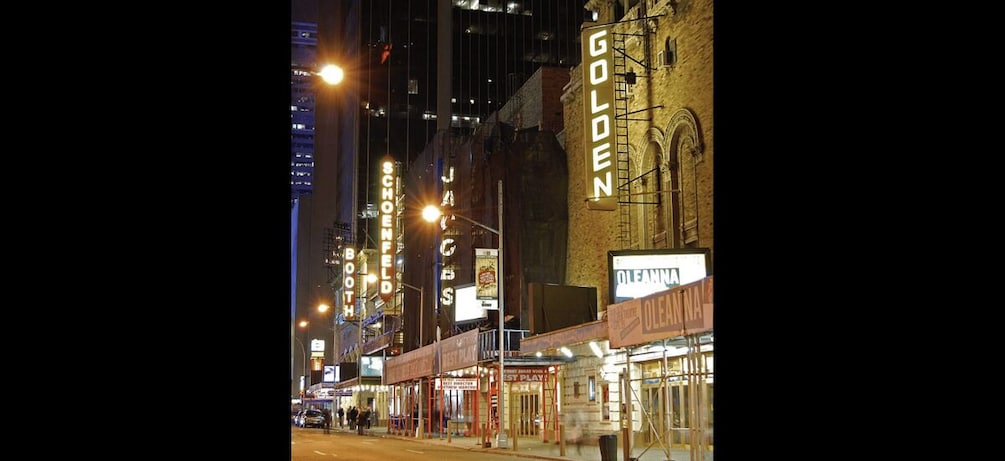 A nighttime street scene with illuminated signs for 'Golden,' 'Jacobs,' and 'Booth.' 2