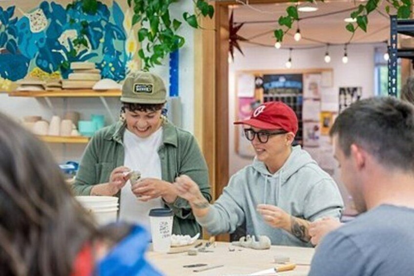 A group of people sitting at a table in a cafe with a colorful mural on the wall. 2