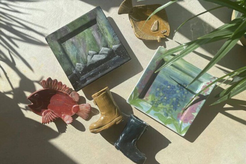 A collection of decorative items including a framed picture, a ceramic fish, a pair of boots, and a bowl with a plant. 5