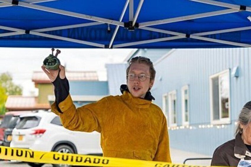 A person holding a green object under a blue canopy with caution tape. 3