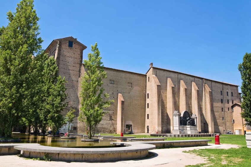 A historic building with a tower, a fountain, and a statue in front. 2