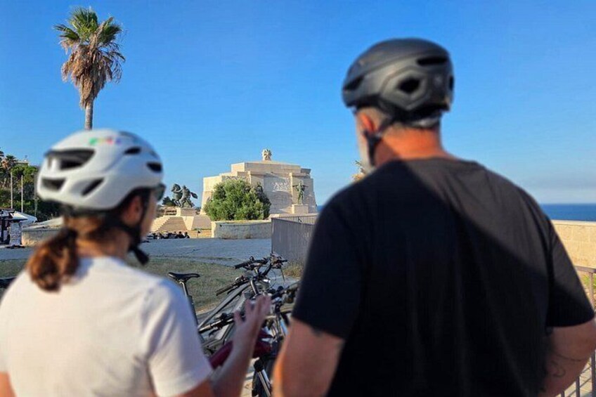 Two people on bicycles, a palm tree, and a building with a statue. 2