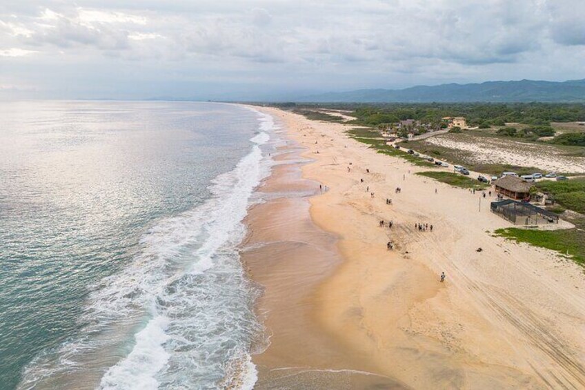 A coastal beach with waves, people, and buildings. 2