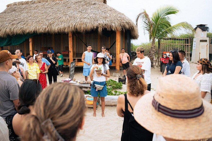 A group of people gathered around a thatched-roof structure, possibly for a tour or event. 5