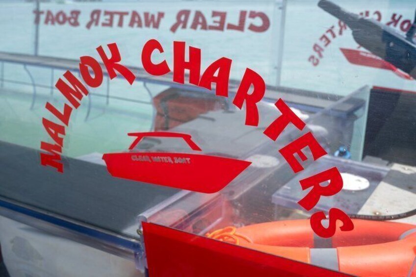 A boat with 'Malmok Charters' and 'Clear Water Boat' text, a red lifebuoy, and a person in the background. 3