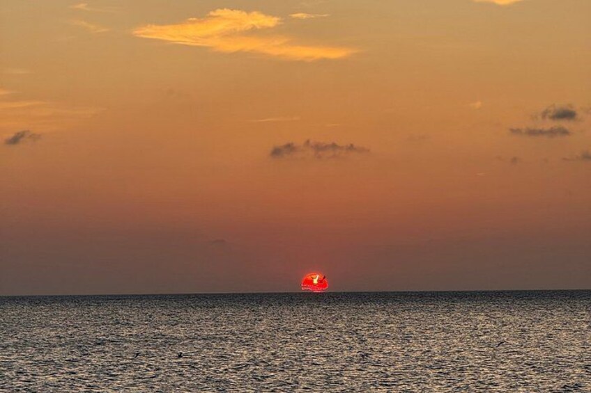 A sunset over a body of water with a red object on the horizon. 3