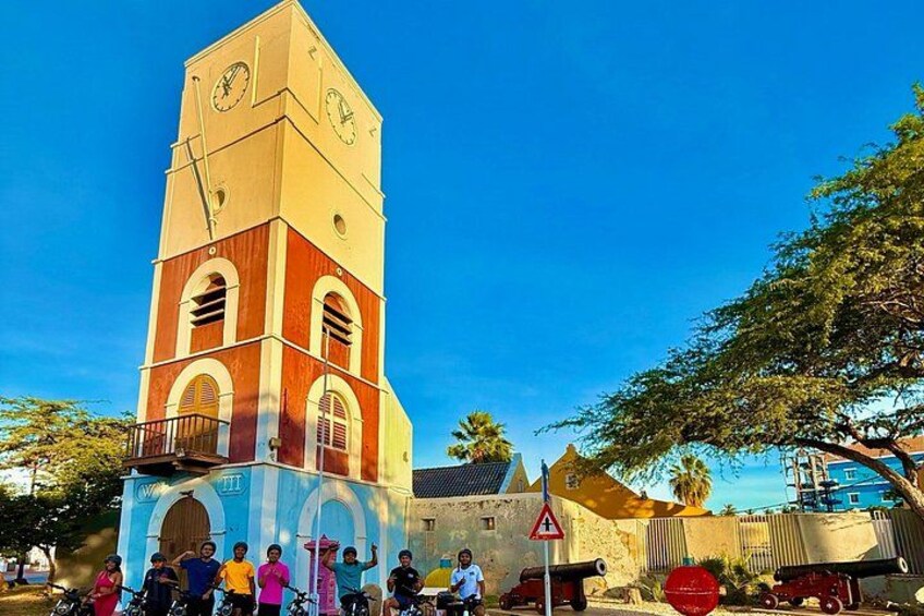 A church with a clock tower, a group of people in front, and a warning sign. 1