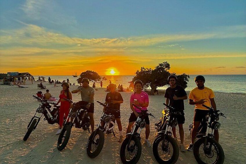 A sunset over a beach with people and bicycles. 5