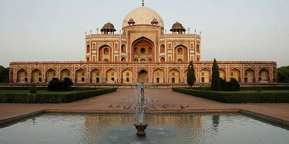 A large, ornate building with a central dome and multiple smaller domes, surrounded by a formal garden and a fountain. 5