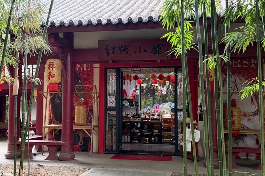 A traditional Chinese shop with red and gold decorations, bamboo plants, and a tiled roof. 2