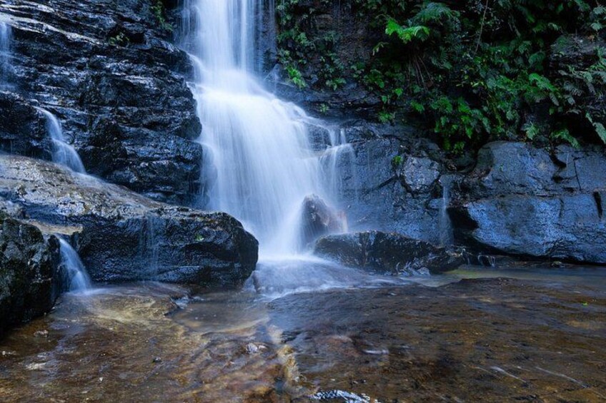 A waterfall cascading over rocks, surrounded by lush greenery. 2