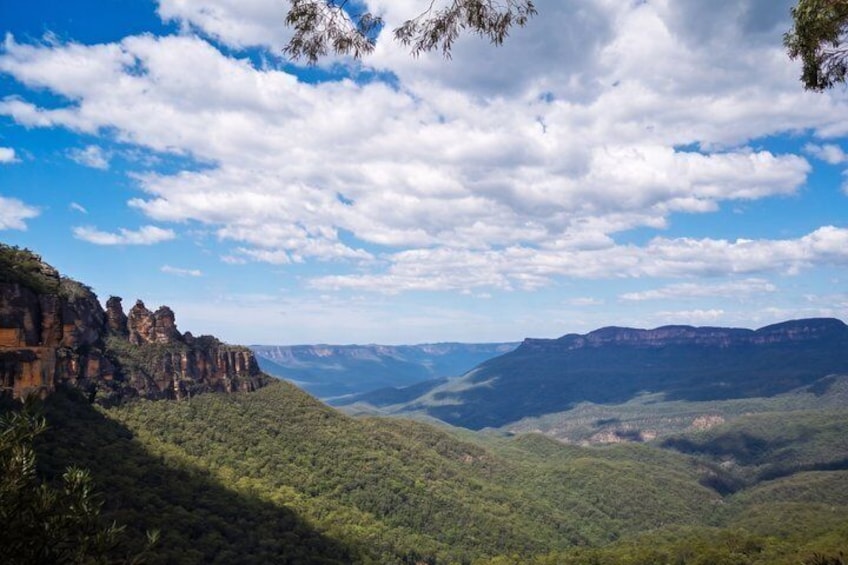 A mountainous landscape with a clear sky and scattered clouds. 1