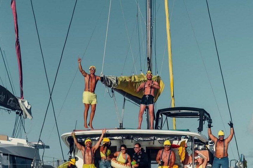 Un groupe de personnes se trouve sur un bateau à voile, certaines d’entre elles portent des chapeaux et des shorts jaunes. 2