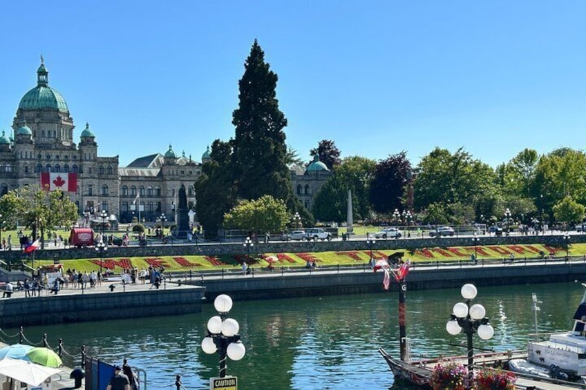 A waterfront with a large building, a row of flags, and a boat docked near the shore. 1