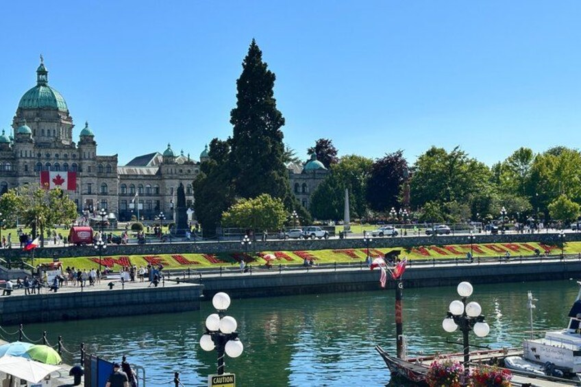 A waterfront with a large building, a bridge, and a row of flags. 1