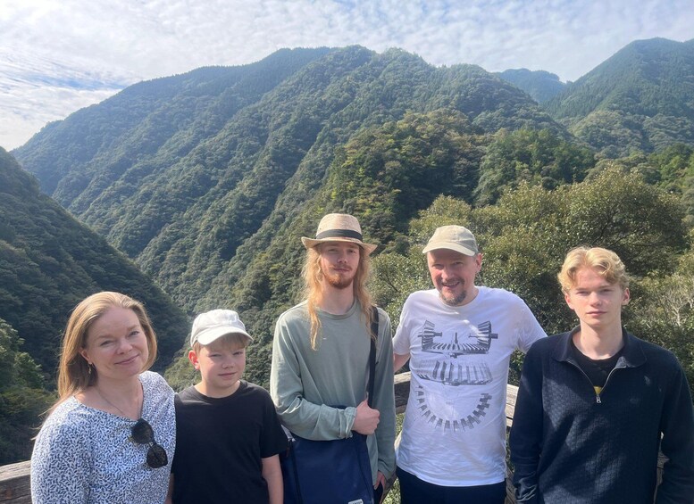 Un grupo de personas de pie sobre una plataforma de madera, con un paisaje montañoso al fondo. 2