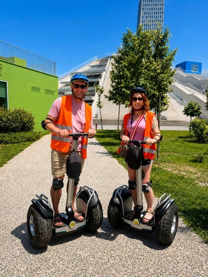 Two people on Segways in a city park with modern buildings in the background. 4