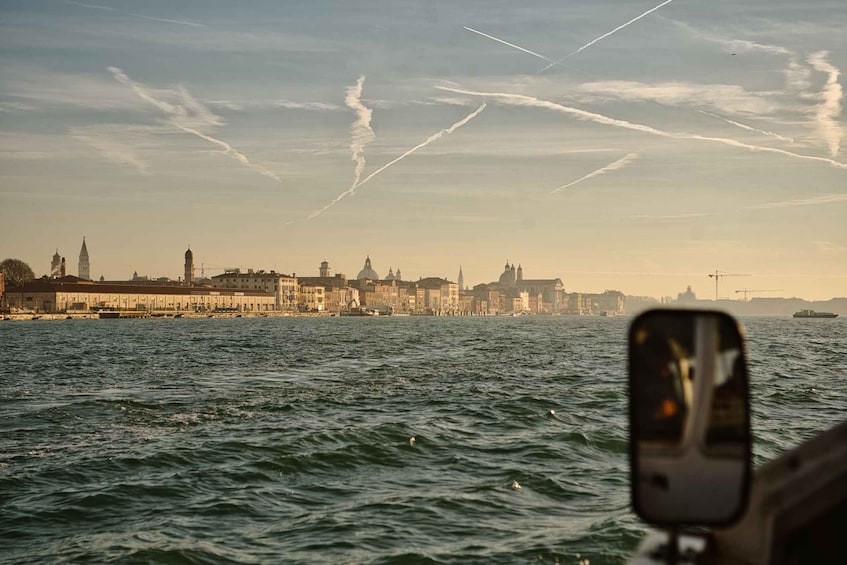 A city skyline across a body of water with a boat's side mirror in the foreground. 4
