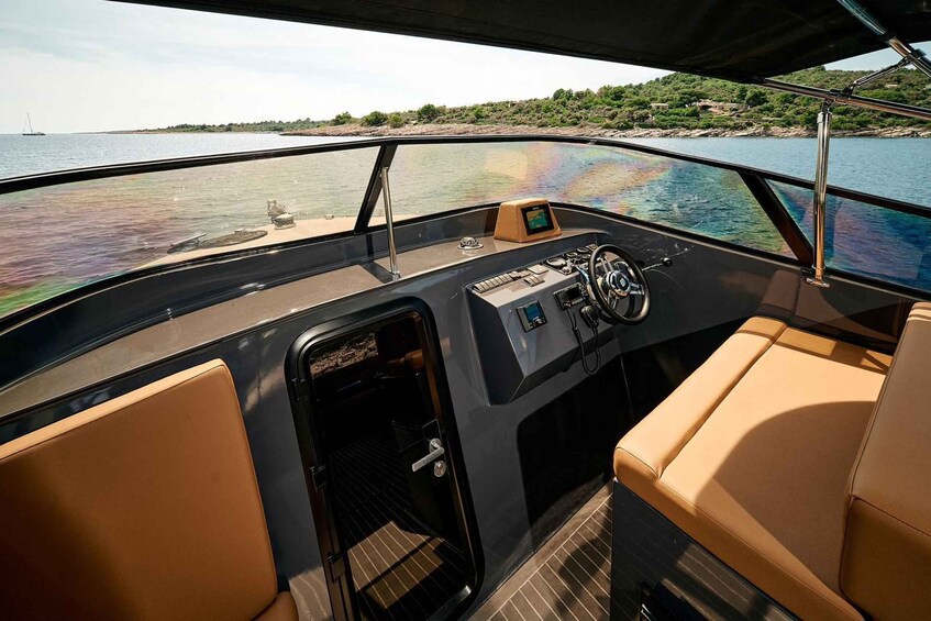 A boat's interior with a steering wheel, control panel, and beige seating. 1