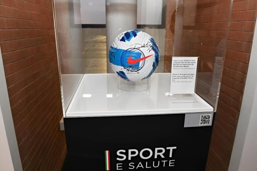 A soccer ball on display with a sign and QR code. 3