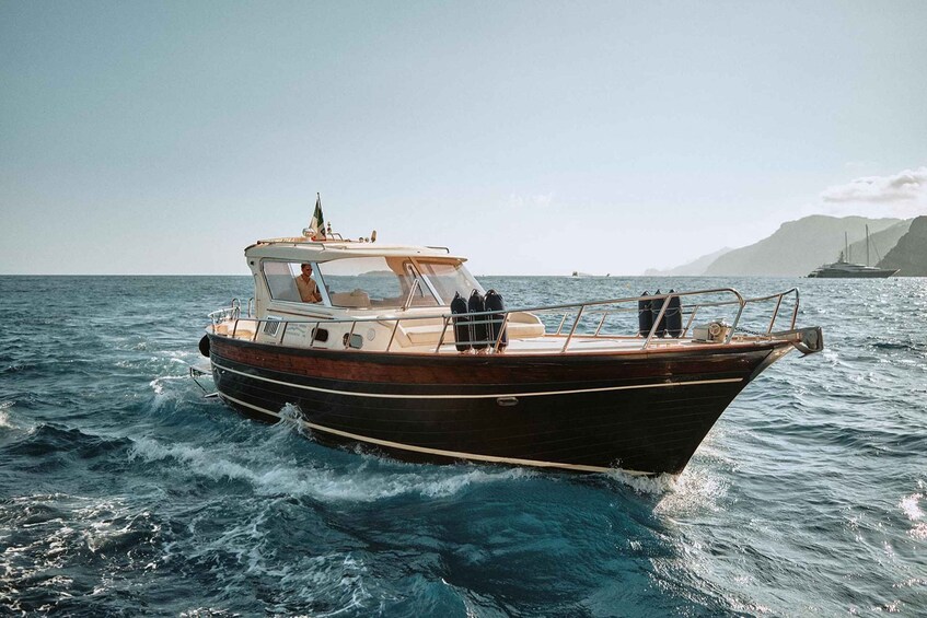 A wooden boat on the ocean with a clear sky and distant land. 3